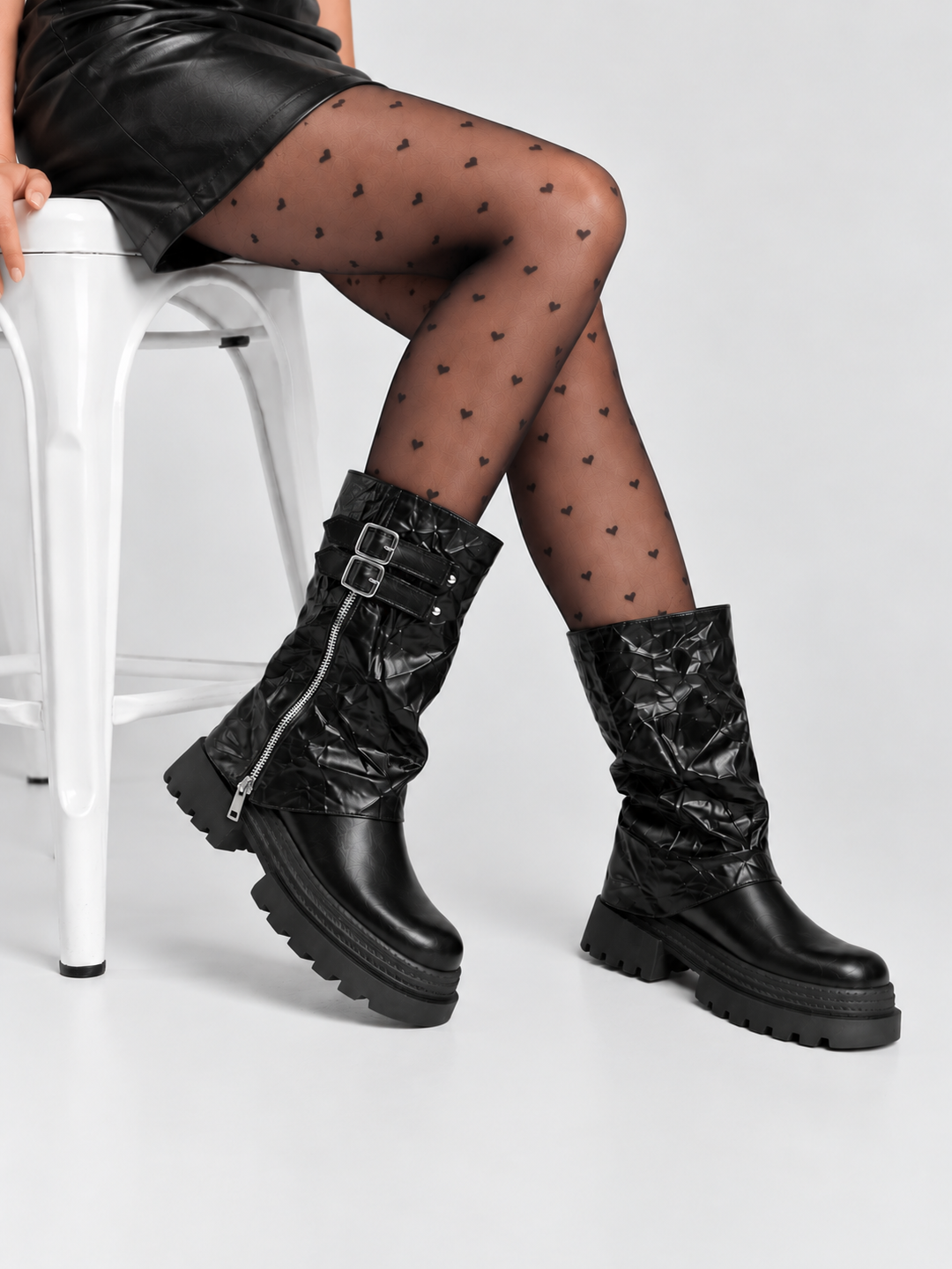 Black crinkled faux leather double-buckle platform boot – worn on model with patterned tights, seated