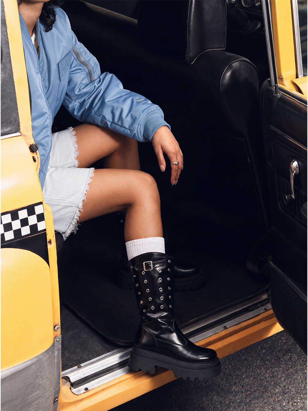 Black faux leather eyelet platform mid-calf boot – worn on model stepping out of a taxi