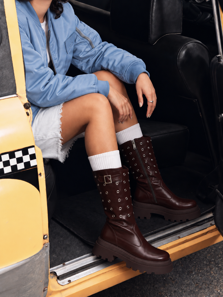 Brown faux leather eyelet platform mid-calf boot – worn on model seated in a taxi
