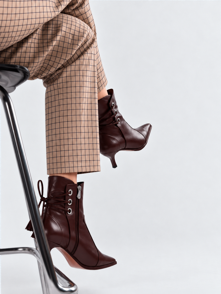 Brown tassel tie kitten heel ankle boot faux leather – worn on model, seated on a stool