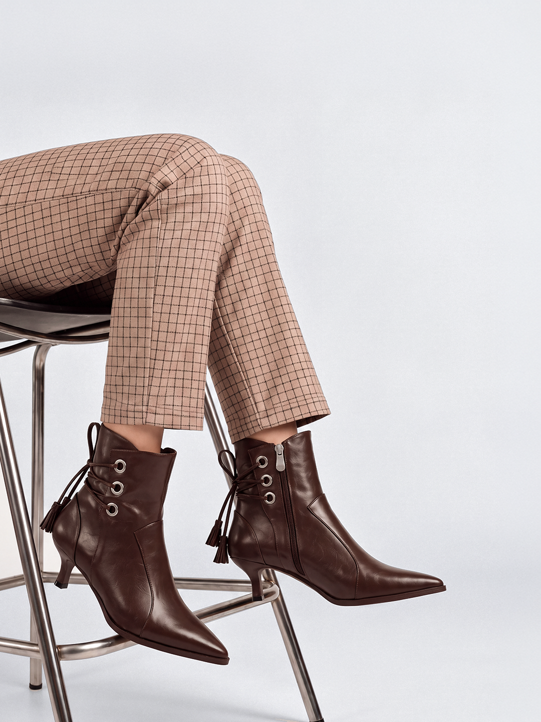 Brown tassel tie kitten heel ankle boot faux leather – worn on model, legs crossed