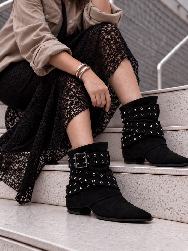 Black faux suede buckle strap slouch ankle boot – worn on model on steps, close-up