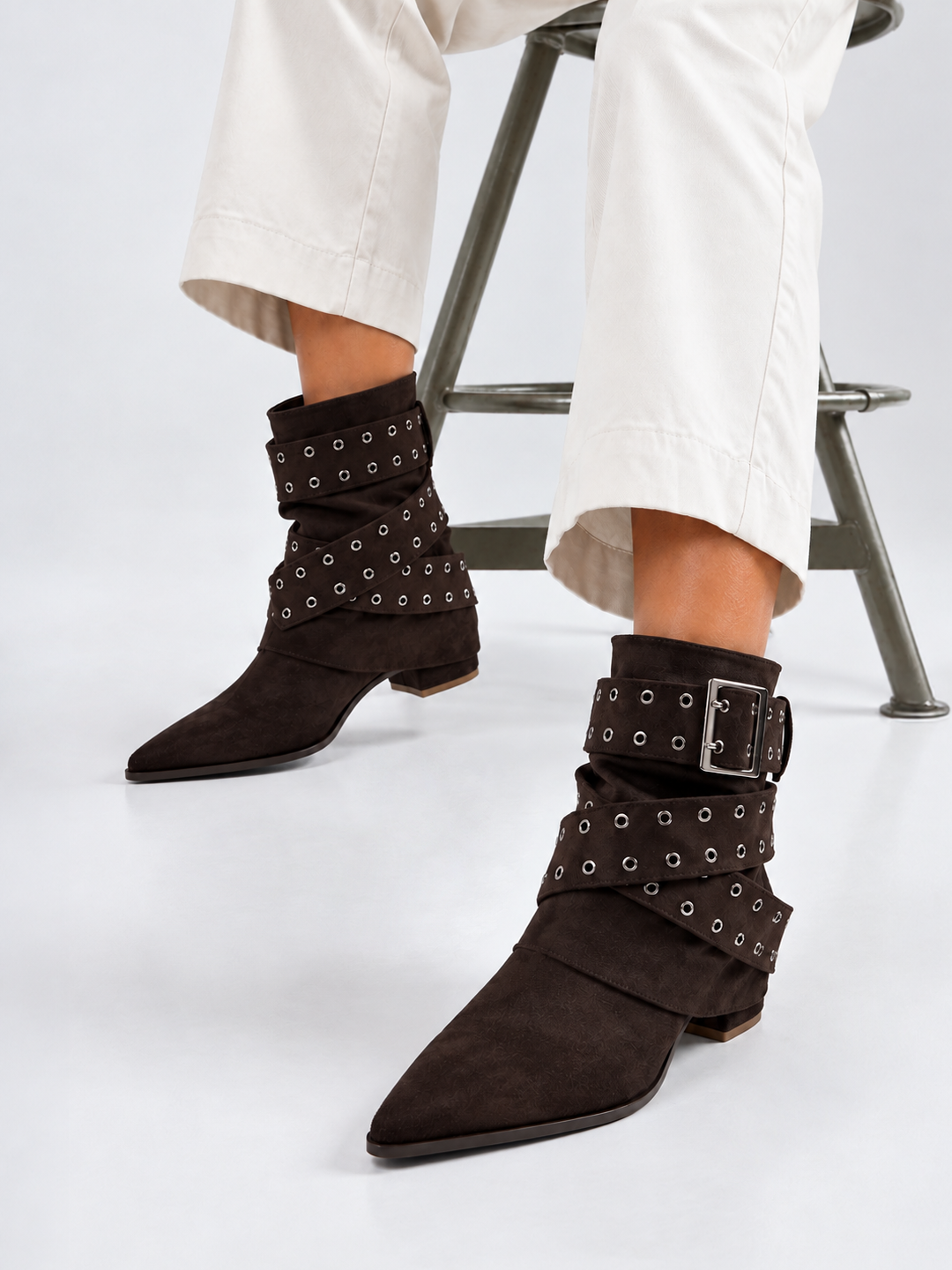 Brown faux suede buckle strap slouch ankle boot – worn on model, seated, front view
