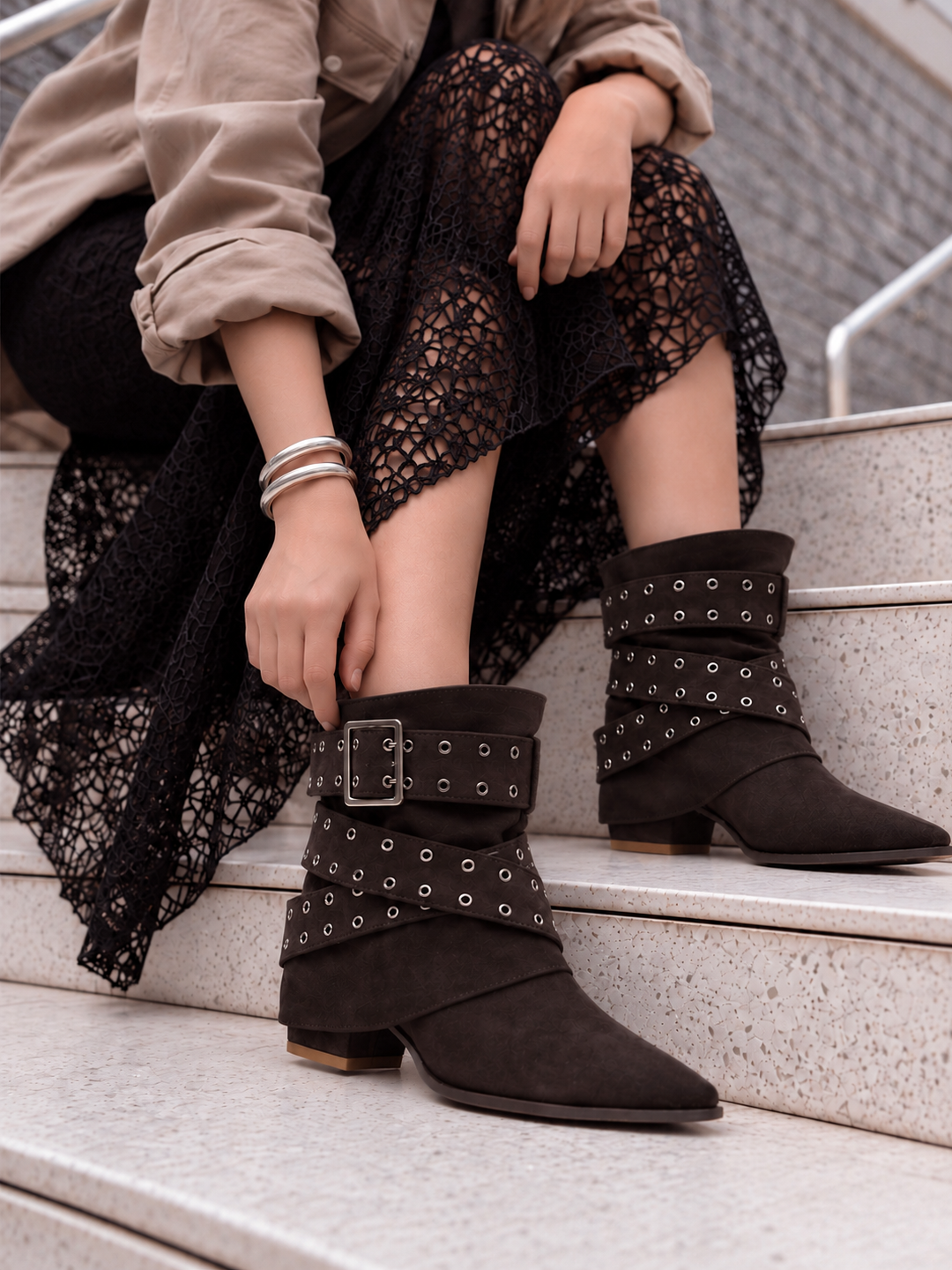 Brown faux suede buckle strap slouch ankle boot – worn on model on steps, close-up