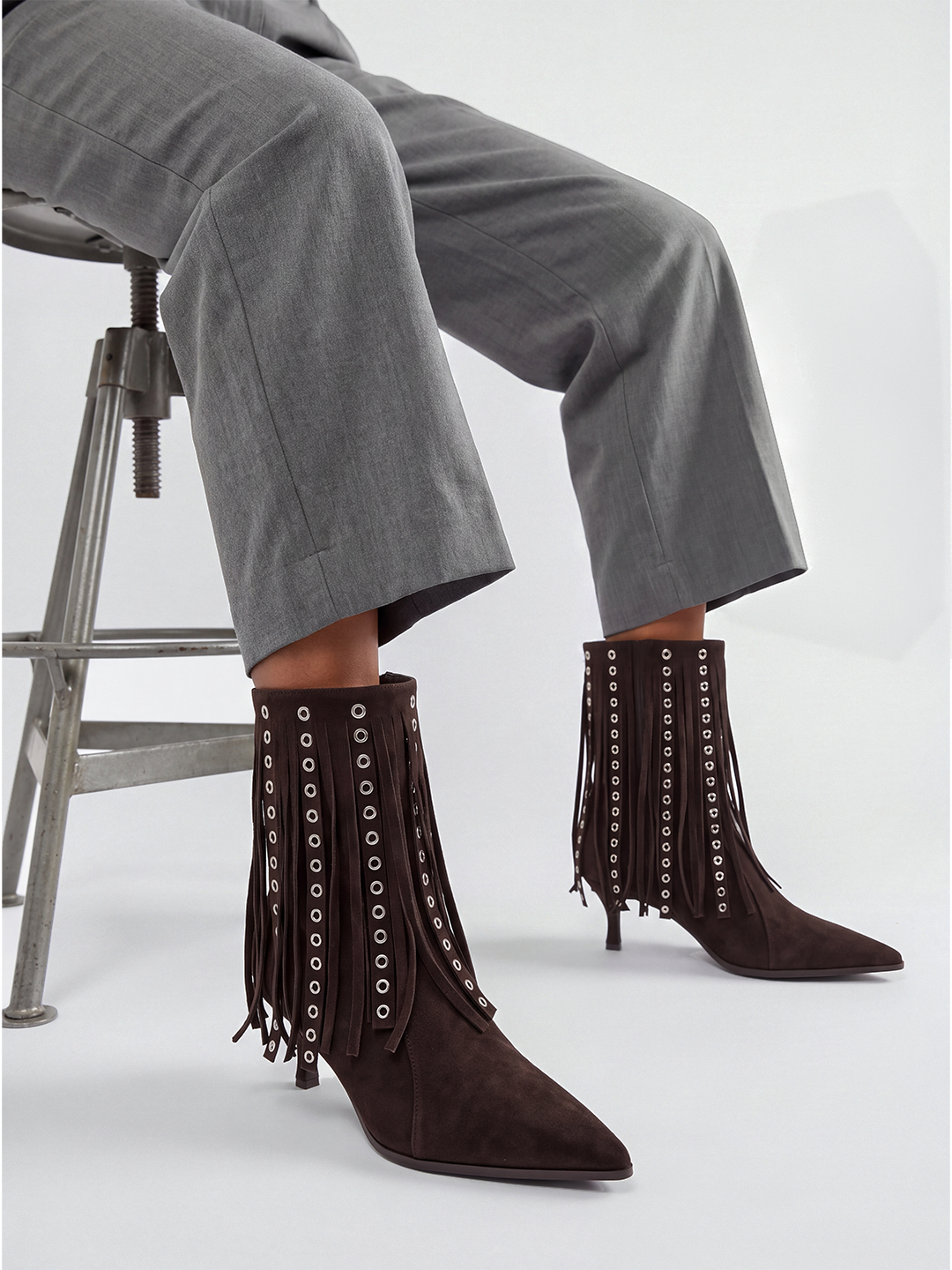 Brown faux suede fringe heeled ankle boot – worn on model, seated, side view