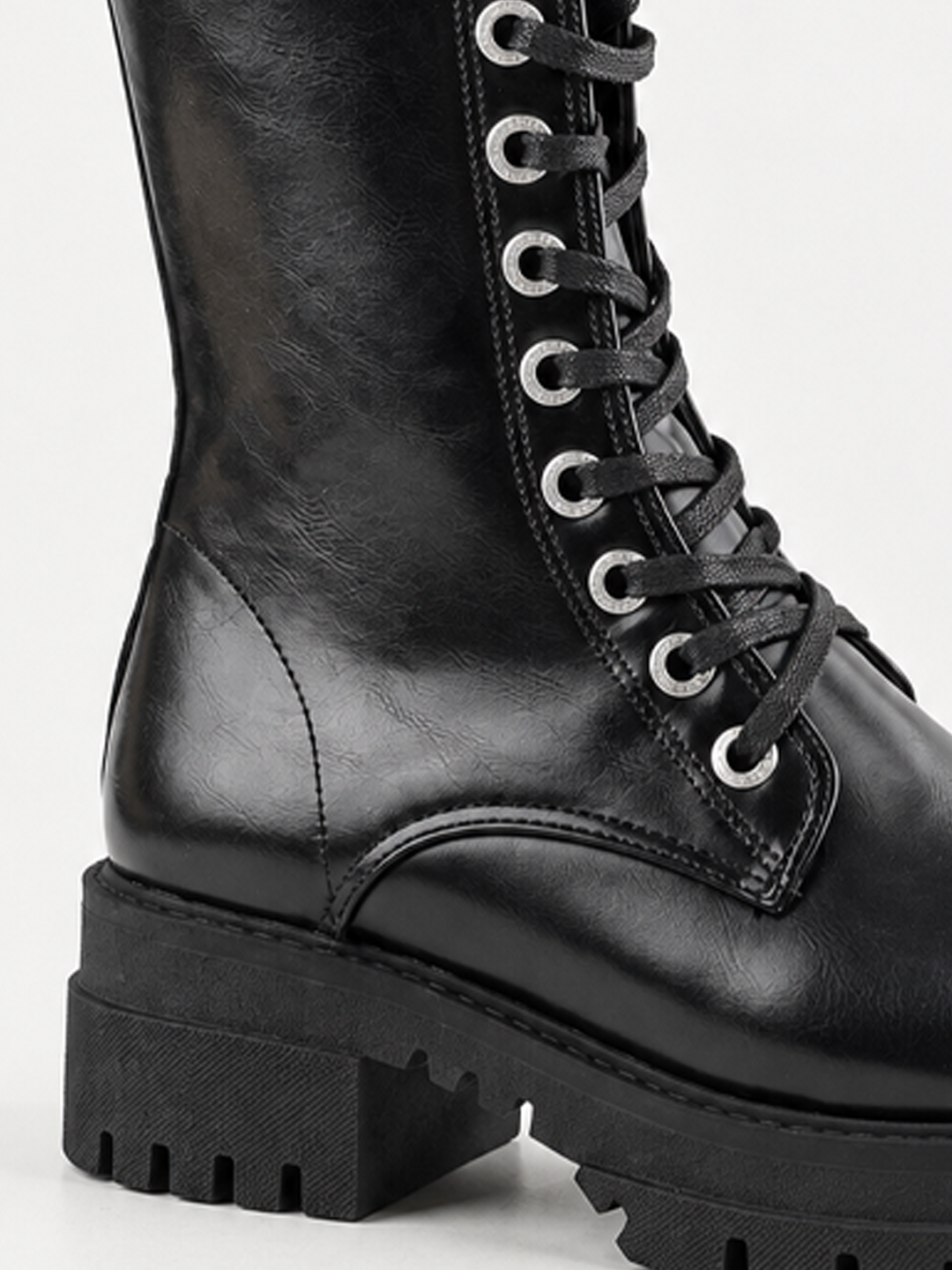 Black mid-calf lace-up combat boot faux leather – laces and lug sole close-up