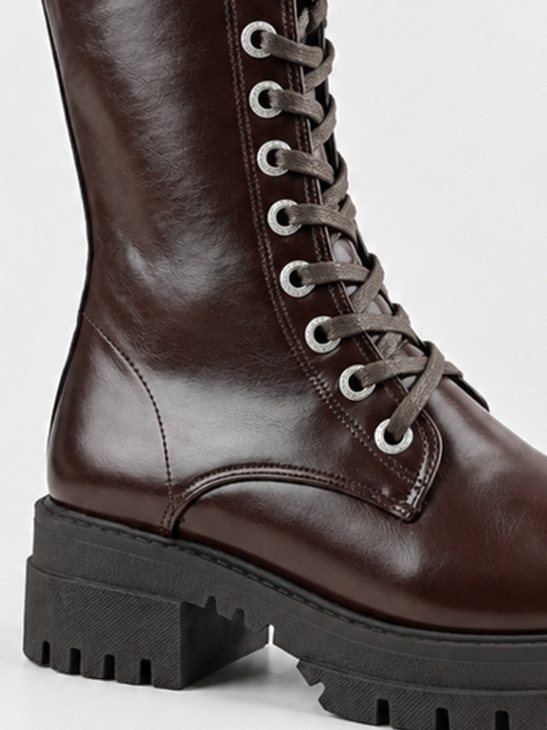Brown mid-calf lace-up combat boot faux leather – laces and lug sole close-up