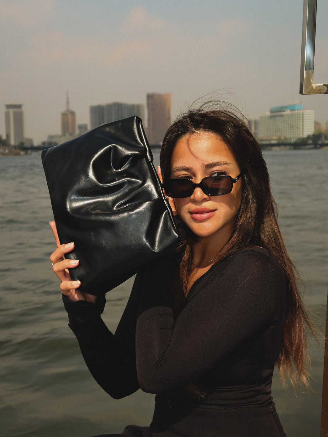Black ruched pouch clutch faux leather – held by model (1)